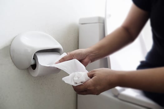 Woman sitting on toilet bowl holding tissue paper  - health problem concept photo