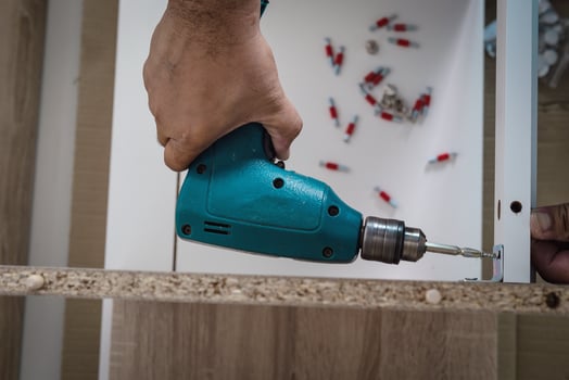Man is working with furniture assembly using electric screwdriver in new house installation - technician onsite work using hand tools concept photo