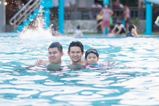 Father and his two son play in clear water swimming pool - happy family play time concept photo