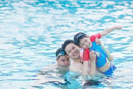 Father and his two son play in clear water swimming pool - happy family play time concept photo
