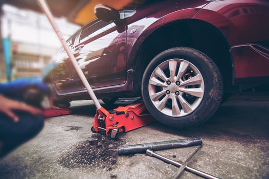 Car tire changed for maintenance in garage using hydraulic jack - car maintenance concept photo