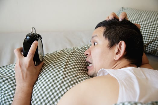 Sleepy man holding the alarm clock in the morning with late wake up - every day life at home concept photo
