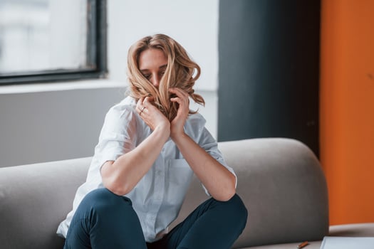 Playful mood. Businesswoman with curly blonde hair sitting in room against window photo