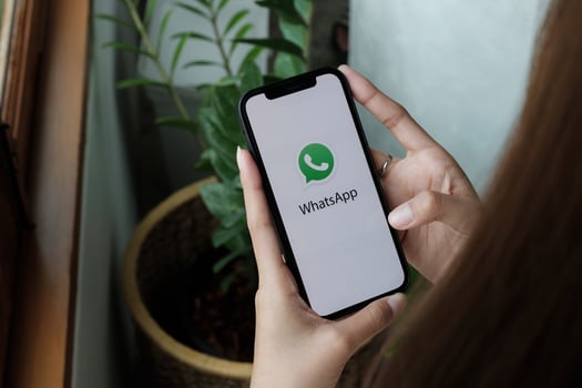 Woman holding iPhone 12 with social networking service WhatsApp on the screen. iPhone was created and developed by the Apple inc photo
