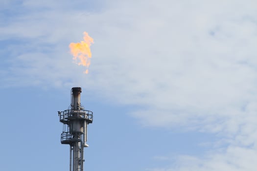 Burning oil flare on a blue sky photo