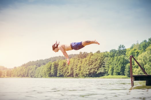 Young fit man making a jump into a lake. photo