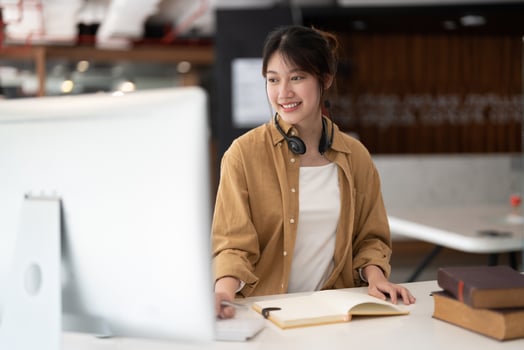 Hipster asian girl school student with wear headphone write notes watch video online webinar learn on laptop sit in bed distance elearning course video conference pc call in bedroom at home photo