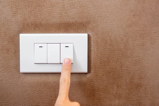 finger turn on or off on light switch on wall at home. Energy Saving, power, electrical and lifestyle concepts photo