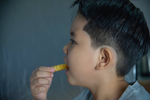 Boy eating French fries potato with dipped sauce over white wooden table photo
