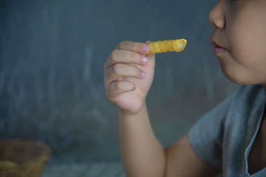 Boy eating French fries potato with dipped sauce over white wooden table photo