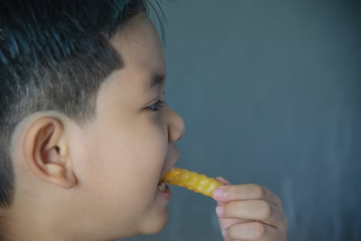 Boy eating French fries potato with dipped sauce over white wooden table photo