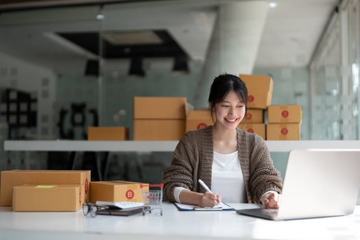 Sell online, Young asian woman checking order and customer's details and addresses on laptop or box in order to prepare for shipping according to the information, Online shopping SME entrepreneur photo