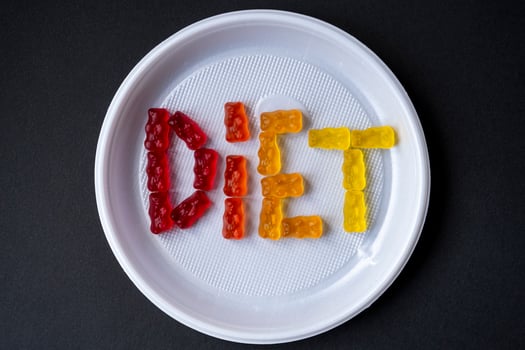 White plastic plate with text DIET from sweet jelly. Sweet fruit gummy bears. Healthy eating, junk food, diet and slimming concept, top view. photo