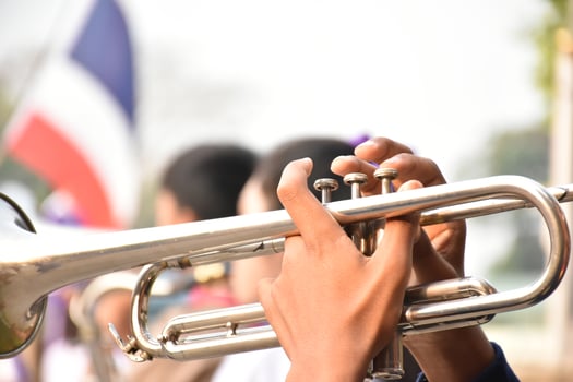 Asian young boy student blowing a trumpet with school marching band, blurred background photo