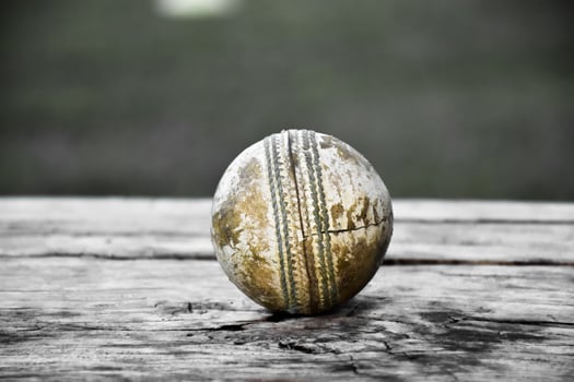 Old training cricket sport equipments on dark floor, leather ball, wickets, helmet and wooden bat, soft and selective focus, traditional cricket sport lovers around the world concept. photo