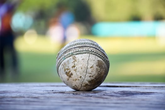 Old training cricket sport equipments on dark floor, leather ball, wickets, helmet and wooden bat, soft and selective focus, traditional cricket sport lovers around the world concept. photo