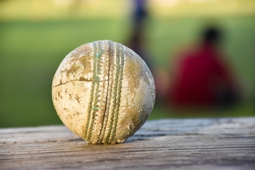Old training cricket sport equipments on dark floor, leather ball, wickets, helmet and wooden bat, soft and selective focus, traditional cricket sport lovers around the world concept. photo