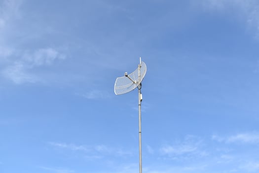 Outdoor internet wifi receiver and repeater antenna on the roof of the building with clear bluesky background. photo