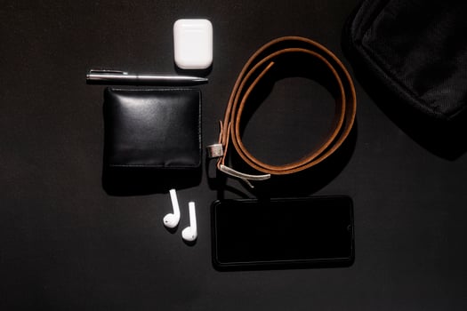 set of men's stuff on black background. smartphone, wireless earphone, leather belt, leather wallet and ballpoint pen photo