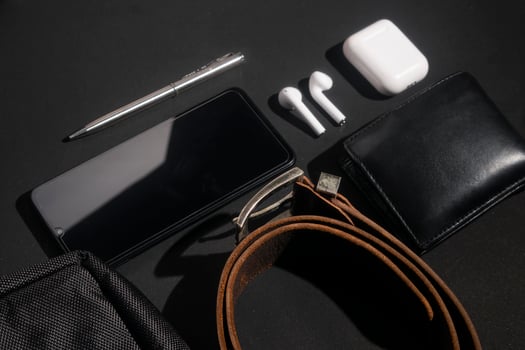 set of men's stuff on black background. smartphone, wireless earphone, leather belt, leather wallet and ballpoint pen photo