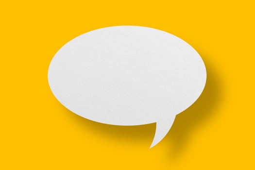 White paper in speech bubble shape set against yellow background. photo