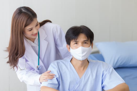 Asian doctor woman talking with a man patient who wear face mask about his health symptom while he sit on wheelchair at hospital. photo