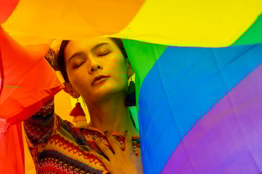 Elegance transgender model woman in colorful rainbow flag costume is dancing in homosexual parade for LGBTQ pride month and coming out of the closet concept for sexual equality and freedom concept photo