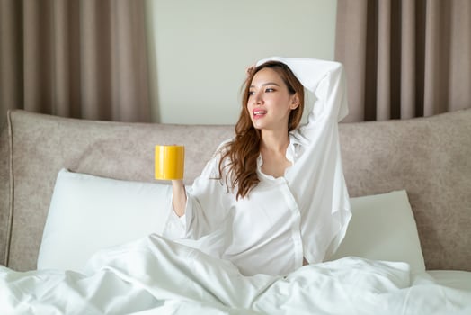 portrait beautiful woman wake up and holding coffee cup or mug on bed photo