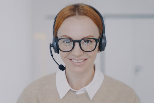 Friendly woman in headphones in call center. Face of happy employee. Customer support concept. photo