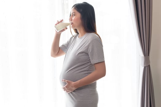 Young pregnant woman drinking milk at home, healthcare and pregnancy care photo
