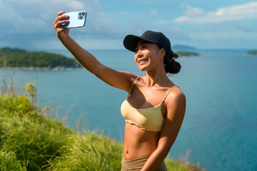 Beautiful asian woman in sportswear taking photo on seaside mountain peak after trekking, Travel and ecotourism concept.