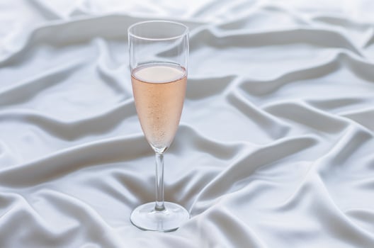 A glass of Rose wine on wavy satin cloth. Stay home concept. photo