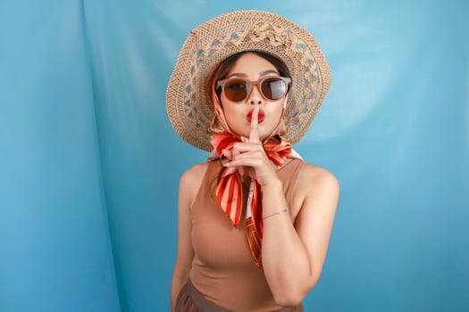 Young Asian happy woman showing be quiet gesture isolated by a blue background photo