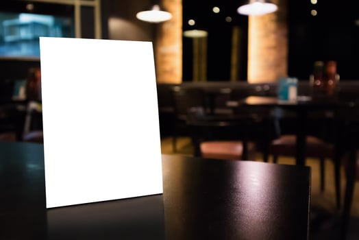 Mockup white label menu frame on table with cafe restaurant interior background photo