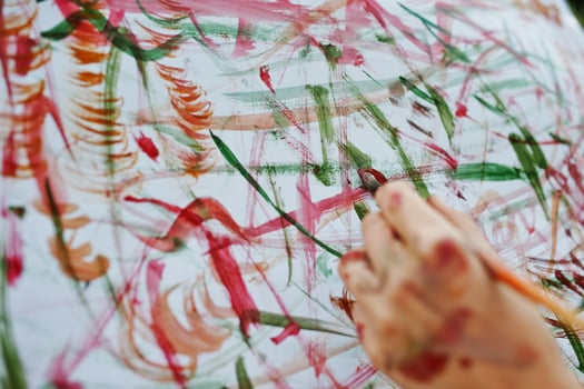 Close-up photo of female hand painting on the paper with watercolors.