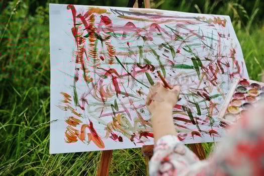 Close-up photo of female hand painting on the paper with watercolors.