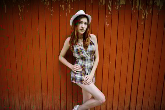 Amazing long legs with hig heels girl wear on hat against wooden background. photo