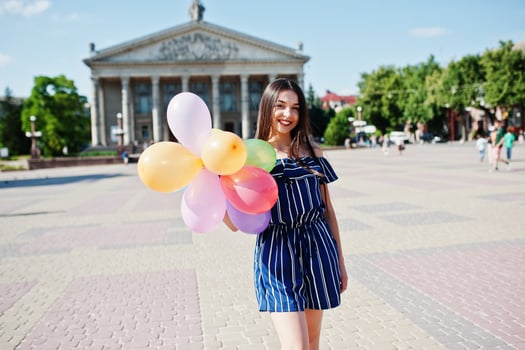 Gorgeous brunette girl at street of city with balloons at hands. photo