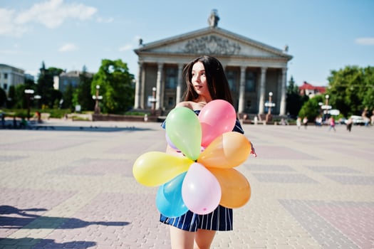 Gorgeous brunette girl at street of city with balloons at hands. photo