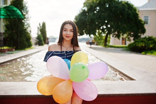 Gorgeous brunette girl at street of city with balloons at hands. photo