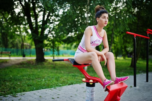 Sport girl wear on white shorts ans shirt doing exercises on simulators outdoor at park. photo