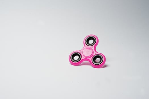 Close-up photo of a pink fidget spinner on a white background.