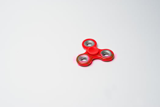 Close-up photo of a red fidget spinner on a white background.