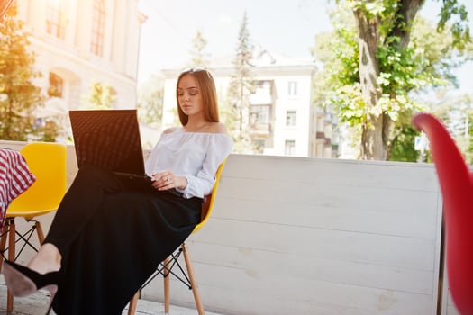 Portrait of a strong independent successful businesswoman wearing smart casual clothing and glasses working on a laptop in a cafe. photo