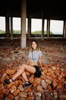 Girl wear on shorts at abadoned factoty sitting on brick. photo