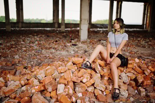 Girl wear on shorts at abadoned factoty sitting on brick. photo