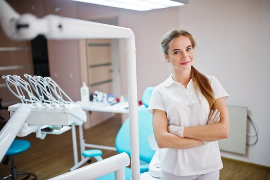 Good-looking female dentist posing in white coat in a modern well-equipped cabinet. photo