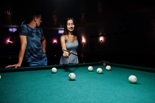 Woman in dress playing pool with a man in a pub. photo