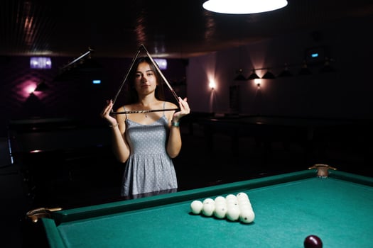 Portrait of a confused woman posing with a triangle by the pool table. photo