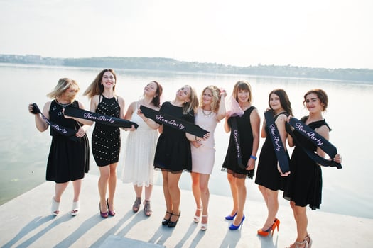 Group of 8 girls wear on black and 2 brides at hen party against sunny beach. photo